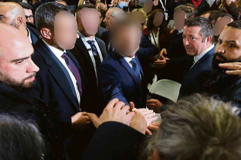Agents de S.F.P.R au contact de la foule autour d'une personnalité, visages floutés